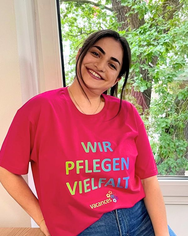 Junge Frau in einem pinken T-Shirt mit der Aufschrift: Wir pflegen Vielfalt