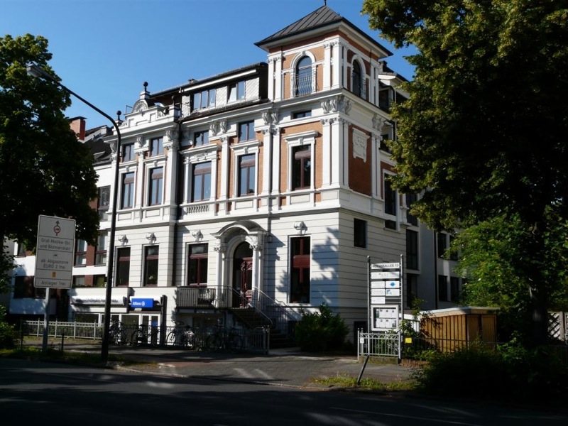 Zentrale vacances Mobiler Sozial- und Pflegedienst in Bremen Historisches, mehrstöckiges Gebäude mit prachtvoller Fassade und Säulen am Eingang, vermutlich eine Einrichtung oder ein Zentrum. Umgeben von Bäumen und Straßenverkehr. Aufnahmewinkel bei Tageslicht mit blauem Himmel.
